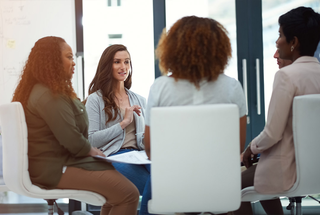 Group of editors sitting in a circle of chairs discussing edits for a state press submitted article.