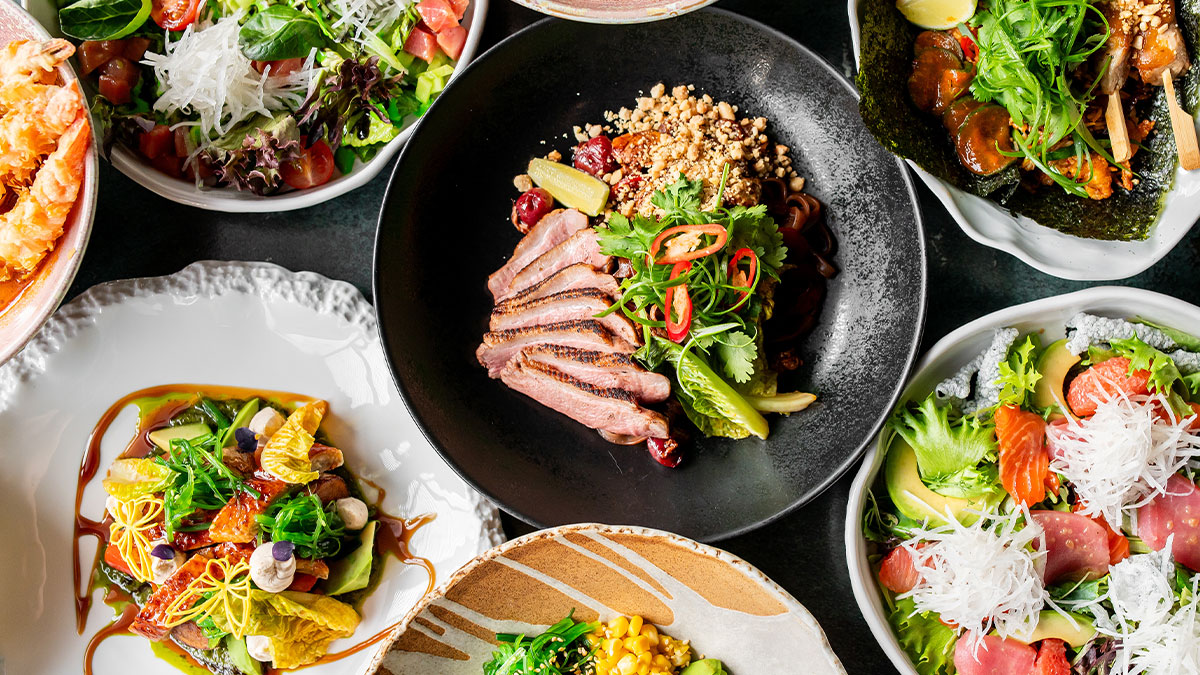 A vibrant assortment of gourmet dishes, including salads, grilled meats, seafood, and colorful garnishes, artfully presented on various plates, showcasing a diverse and appetizing culinary spread
